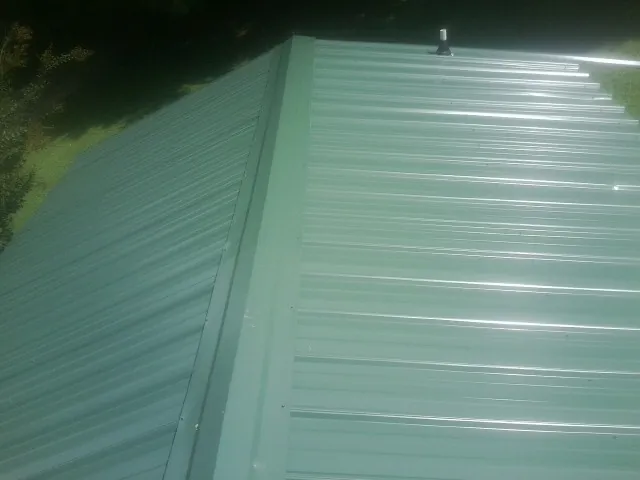 New green metal panels meeting at the ridge of a roof — Flat Roof Repair work by our crew in Donegal