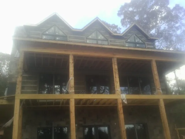 Dormers and porch framing on a large log home under construction — Roof Coating work by our crew in Donegal