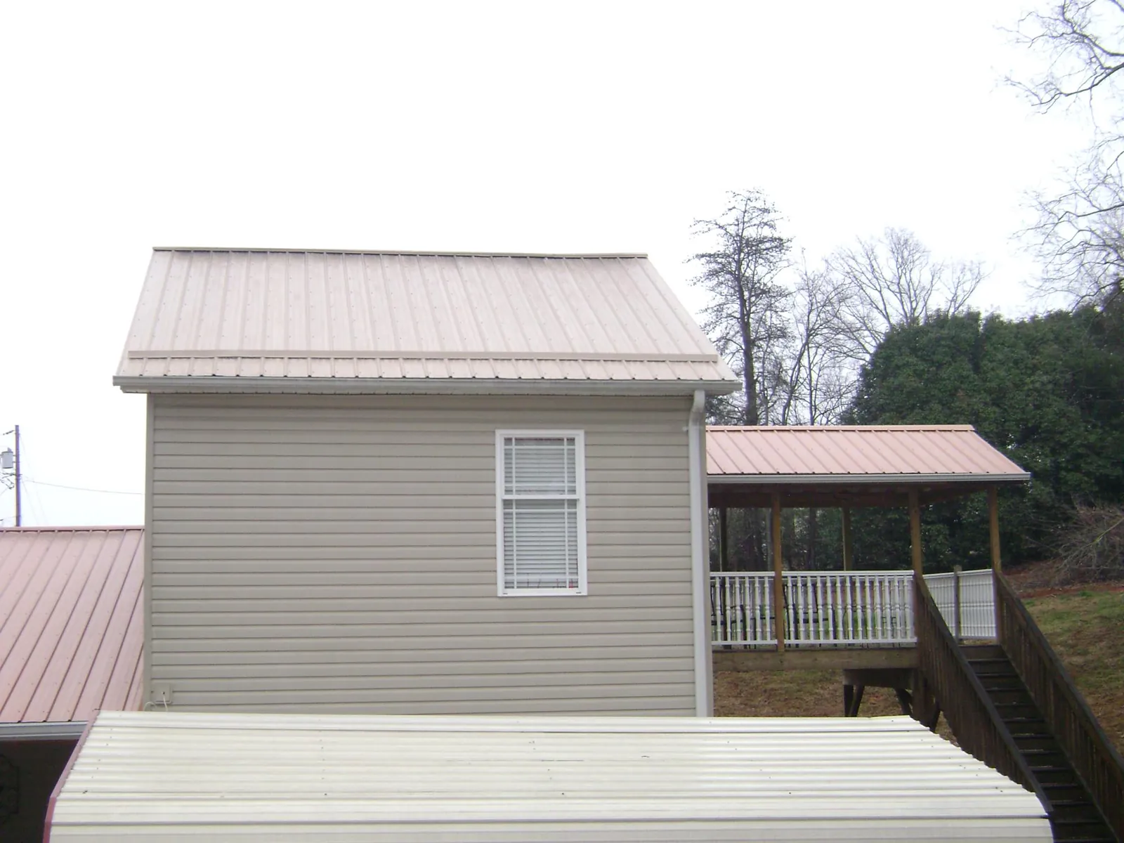 Tan metal roofs on a two story addition and attached porch, from a Roof Replacement job in Donegal