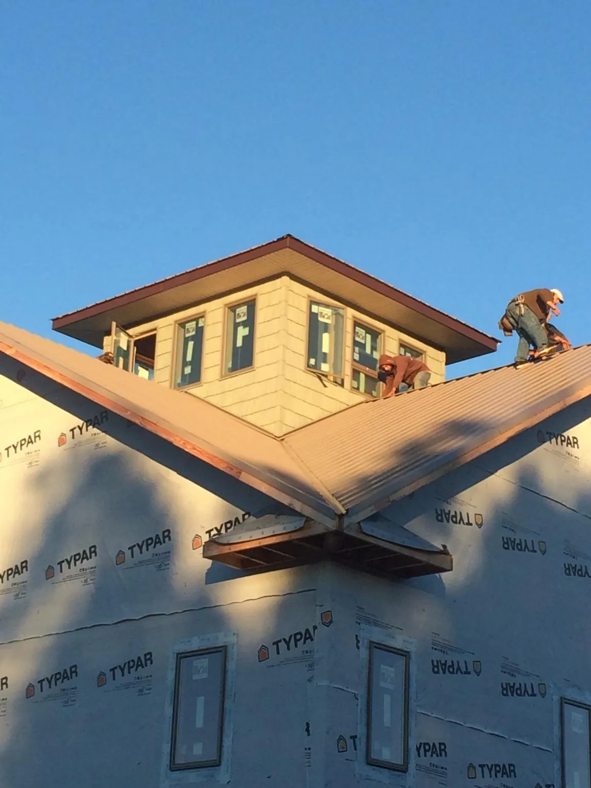 Roofers working around a rooftop cupola on a new metal roof at sunset — Roof Waterproofing in Donegal by Roofing Brothers